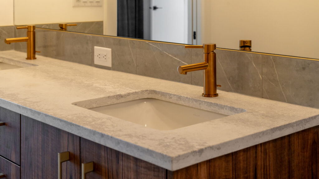 White color washroom stone with rough look with gold vanities.
